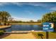 Scenic community lake with a dock, blue sky, and trees and a sign that reads 