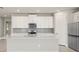 Bright kitchen featuring white cabinets, stainless steel appliances, and a gray backsplash at 17901 Solstice Ave, Venice, FL 34293