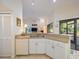 White kitchen cabinets, double sink, and view into living room at 207 Lighthouse Ct, Safety Harbor, FL 34695