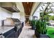Outdoor kitchen features stainless steel grill, sleek countertops, and lush greenery, perfect for outdoor cooking at 4518 W Rosemere Rd, Tampa, FL 33609