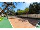 Well-maintained tennis court with surrounding landscaping and partial shade at 4518 W Rosemere Rd, Tampa, FL 33609