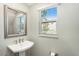 Small bathroom with pedestal sink, mirror, and window at 4587 Almada Ln, Wesley Chapel, FL 33543