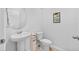 Small bathroom with pedestal sink, toilet, and a round mirror at 7689 Imagination Pl, Wesley Chapel, FL 33545