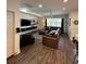 Living room with brown couch, wood-look tile floors, and entertainment center at 1449 Kaffir Lily Ct, Trinity, FL 34655