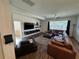 Living room with leather sectional sofa, wood-look flooring, and large windows at 1449 Kaffir Lily Ct, Trinity, FL 34655