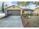 Cute ranch home with a well-maintained yard and a brown garage door at 7418 Riverbank Dr, New Port Richey, FL 34655