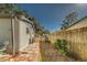Brick pathway leads to a gate in a side yard with plants at 1638 St Catherine W Dr, Dunedin, FL 34698