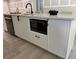 Close up of a kitchen island featuring white cabinets, quartz countertops, and a black faucet and microwave at 4202 N 15Th St, Tampa, FL 33610