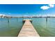 Long, weathered dock leading into serene waters under a sunny, clear sky at 817 Bay Point Dr, Madeira Beach, FL 33708