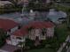 Elegant home with a red tile roof overlooking a serene lake with a lit fountain at dusk at 1414 Alhambra Dr, Apollo Beach, FL 33572
