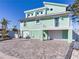 Two-story light teal home with paver driveway and garage at 17410 1St E St, Redington Shores, FL 33708