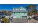 Two-story light teal house with gray roof, paved driveway and boat dock at 17410 1St E St, Redington Shores, FL 33708