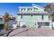 Two-story light teal home with metal roof and paved driveway at 17410 1St E St, Redington Shores, FL 33708