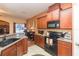 Modern kitchen with dark wood cabinets, black appliances, and an island at 8423 Blue Rock Dr, New Port Richey, FL 34653