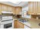 Condo kitchen with light wood cabinets, white appliances, and granite countertops at 2400 Winding Creek Blvd # 24-203, Clearwater, FL 33761