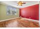 Bedroom with a ceiling fan, wood floors, and a red accent wall at 3306 N Howard Ave, Tampa, FL 33607