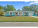 Charming, bright blue single-story home with a well-manicured front lawn and light pink front door at 6500 7Th S Way, St Petersburg, FL 33705