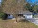 House exterior with a tree in front, attached garage and neat lawn at 5925 Wilson Dr, Zephyrhills, FL 33542