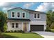 Two-story home with gray and teal siding, a dark garage door, and landscaping at 12288 Cattleside Dr, Riverview, FL 33579