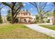 Rear view of the home featuring a deck, patio, and lush backyard with mature trees and landscaping at 4611 W Lowell Ave, Tampa, FL 33629