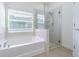 Bathroom featuring a tub and frameless shower with tiled floors and a window at 5709 White Trillium Loop, Land O Lakes, FL 34639