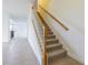 Carpeted staircase with wooden banister, landing, and adjacent living area at 5709 White Trillium Loop, Land O Lakes, FL 34639