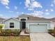 Single-story home with light blue exterior, two-car garage, and landscaping at 7139 Steer Blade Dr, Zephyrhills, FL 33541