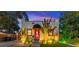 Charming bungalow with a red door, and well-landscaped front yard at dusk at 727 53Rd N Ter, St Petersburg, FL 33703