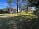 Expansive backyard with green lawn, mature trees, screened patio, and partial fence at 11405 Warm Wind Way, Weeki Wachee, FL 34613