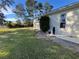 View of house with manicured lawn, green bushes, exterior utilities, and large window at 11405 Warm Wind Way, Weeki Wachee, FL 34613