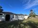 Stucco home exterior featuring an enclosed patio with pool with well-maintained lawn and blue skies at 11405 Warm Wind Way, Weeki Wachee, FL 34613