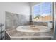Oval soaking tub with tiled surround in a well lit bathroom at 19301 Sandy Springs Cir, Lutz, FL 33558