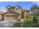 Two-story house with tan exterior, two-car garage, and landscaping at 19301 Sandy Springs Cir, Lutz, FL 33558