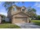 Two-story tan house with attached garage and a small front yard at 19301 Sandy Springs Cir, Lutz, FL 33558