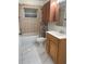Updated bathroom with wood cabinets, a bathtub, and marble-look flooring at 8601 Twin Lakes Blvd, Tampa, FL 33614