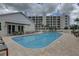 Community pool with surrounding patio furniture and building view at 1200 Country Club Dr # 2504, Largo, FL 33771