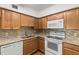 Kitchen with wood cabinets, granite counters, and white appliances at 2262 Swedish Dr # 12, Clearwater, FL 33763