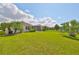 Spacious backyard with grassy lawn, screened patio, and palm trees at 6836 Park Strand Dr, Apollo Beach, FL 33572