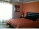 Bright bedroom with orange accent wall, comfortable bed, and window coverings at 18235 Bridle Club Dr # 18235, Tampa, FL 33647