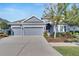 Single-story home with gray exterior, three-car garage, and landscaped yard at 7506 Parkshore Dr, Apollo Beach, FL 33572