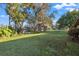 Expansive backyard with mature trees, lush green lawn, and waterfront views, perfect for outdoor enjoyment and relaxation at 905 Lake Fuller Dr, Lutz, FL 33548