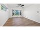 Bright bedroom featuring a large window with a view of the lake, a ceiling fan, and hardwood floors at 905 Lake Fuller Dr, Lutz, FL 33548
