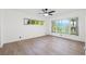 Bright bedroom featuring wood-look floors, a ceiling fan, and large windows providing lots of natural light at 905 Lake Fuller Dr, Lutz, FL 33548