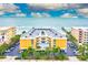 Aerial view of beachfront condo building with ocean and pier views, parking, and lush landscaping at 16308 Gulf Blvd # 303, Redington Beach, FL 33708