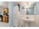 Clean bathroom with pedestal sink, light blue walls, and linen cabinet at 20735 Gardenia Dr, Land O Lakes, FL 34638