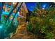 Lighted pathway leads to a lush, tropical backyard with stone accents at 711 Pinellas Point S Dr, St Petersburg, FL 33705