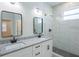 Bathroom featuring double sink with granite countertop and modern shower with glass door at 8317 N Ogontz Ave, Tampa, FL 33604