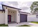 Inviting entryway showcasing a gray garage door, red front door and modern architectural details at 8317 N Ogontz Ave, Tampa, FL 33604