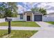 Charming home featuring a gray garage door, red front door and well-maintained green lawn at 8317 N Ogontz Ave, Tampa, FL 33604