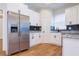 Bright kitchen features stainless steel refrigerator and appliances, white cabinetry, and wood-look flooring at 8317 N Ogontz Ave, Tampa, FL 33604